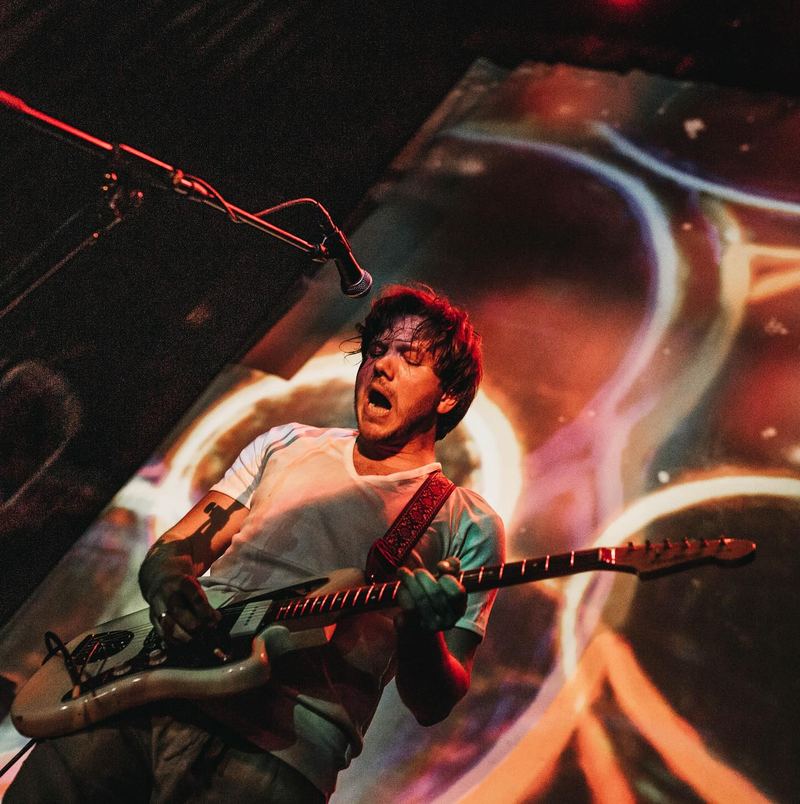 Singer and guitarist mid-shout under coloured lights
