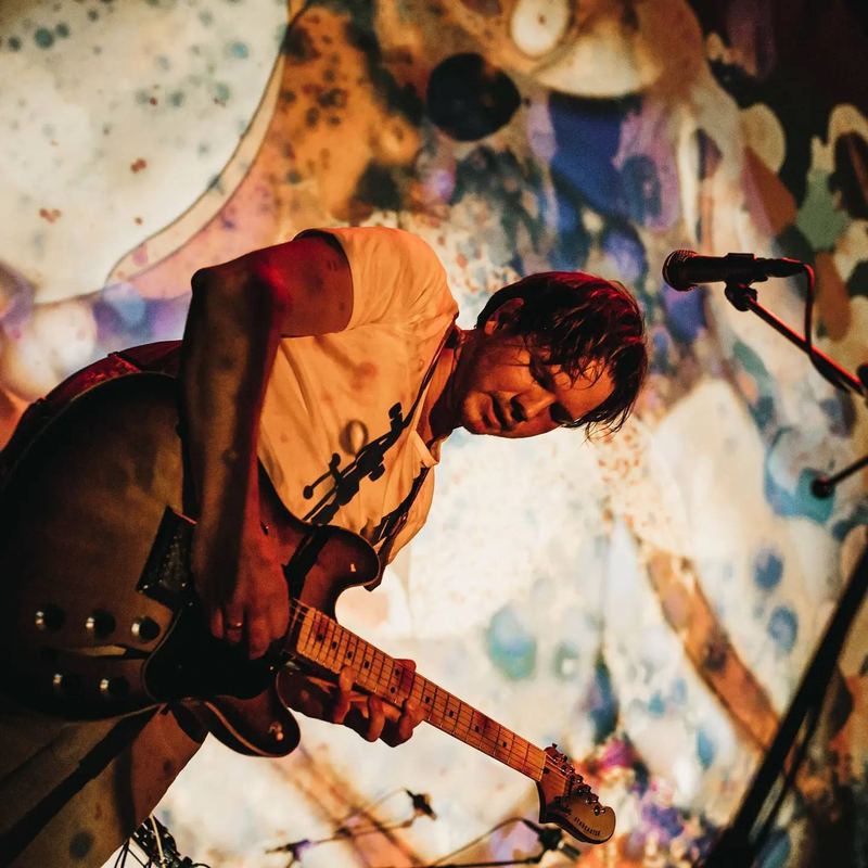 Guitarist bent over his guitar with liquid light projections