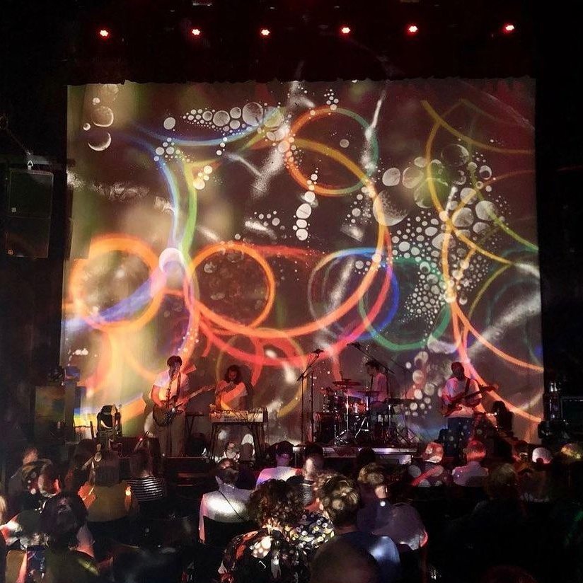 The band on a big stage with the album artwork projected behind them